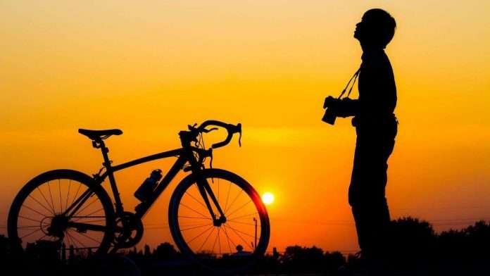 Are we Living man standing besides a cycle